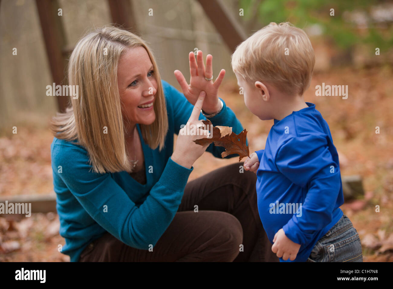 Frau, die das Wort "Leaf" in amerikanischer Gebärdensprache während der Kommunikation mit ihrem Sohn Unterzeichnung Stockfoto