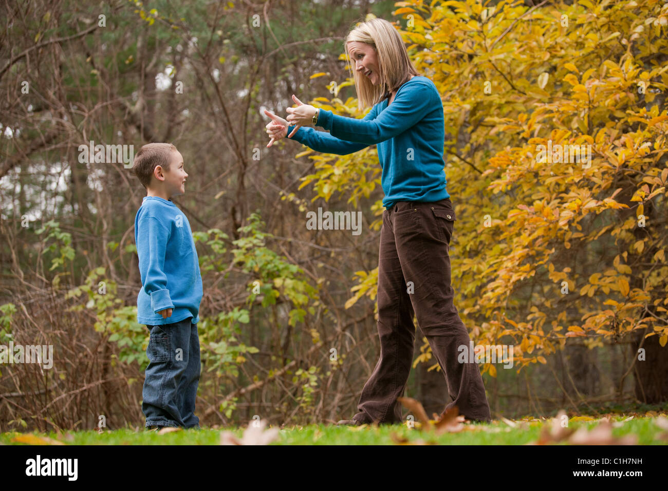 Frau, die das Wort "Play" in amerikanischer Gebärdensprache während der Kommunikation mit ihrem Sohn Unterzeichnung Stockfoto