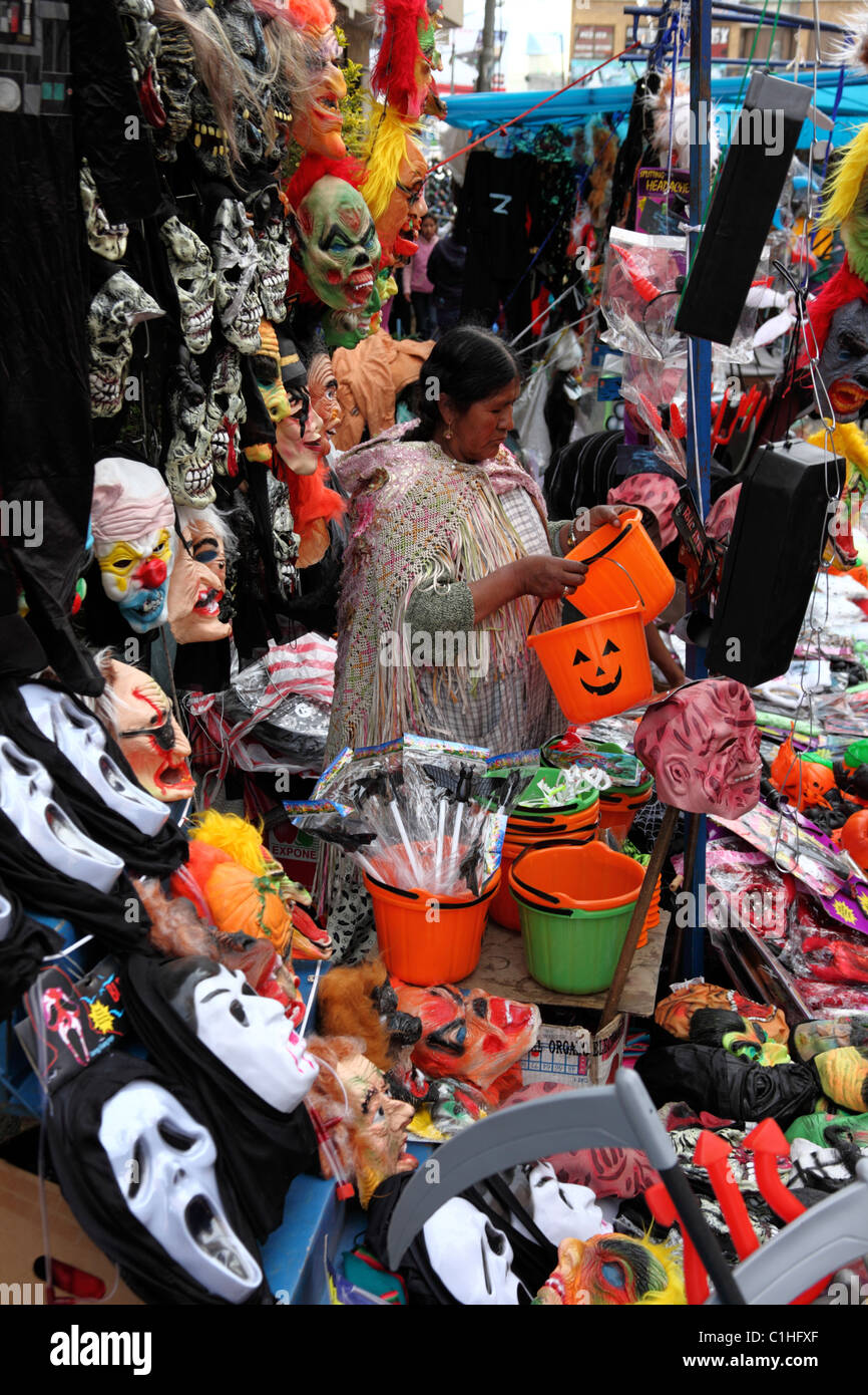 Aymara-Frau verkauft Masken (einschließlich Ghostface Masken aus den Scream-Filmen), Kostüme und Gegenstände für Halloween auf dem Straßenmarkt in La Paz, Bolivien Stockfoto