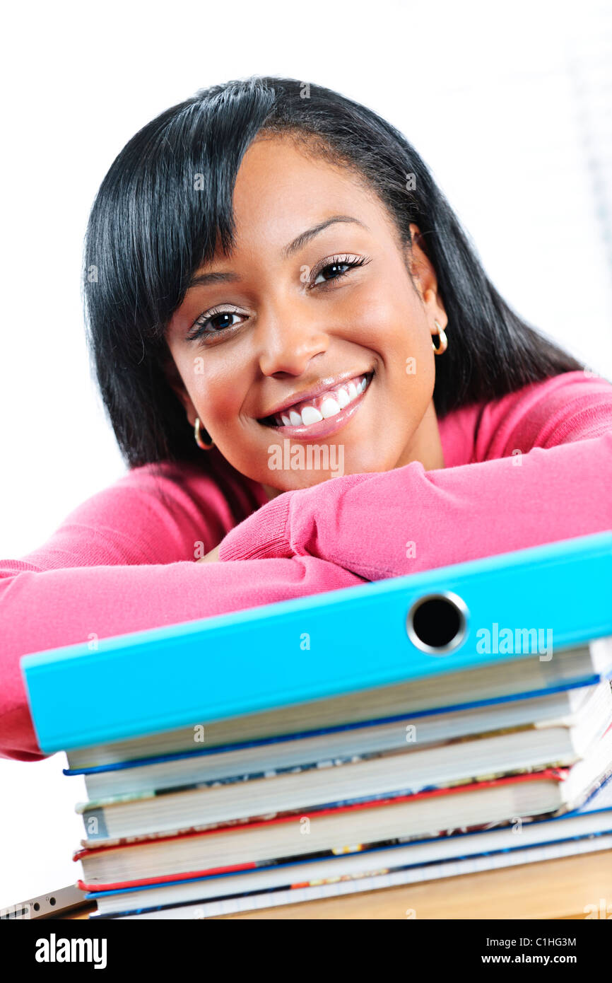 Lächelnde junge schwarze Studentin mit Lehrbüchern auf Schreibtisch Stockfoto