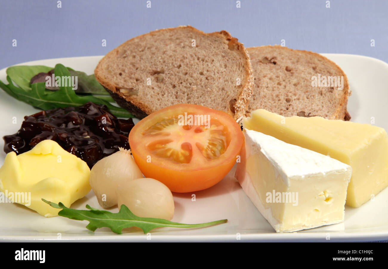 Ploughmans Lunch serviert mit frischen Getreidespeicher Brot und eine Auswahl an Käse, frische Tomaten, eingelegte Zwiebeln und Essiggurke chutney Stockfoto