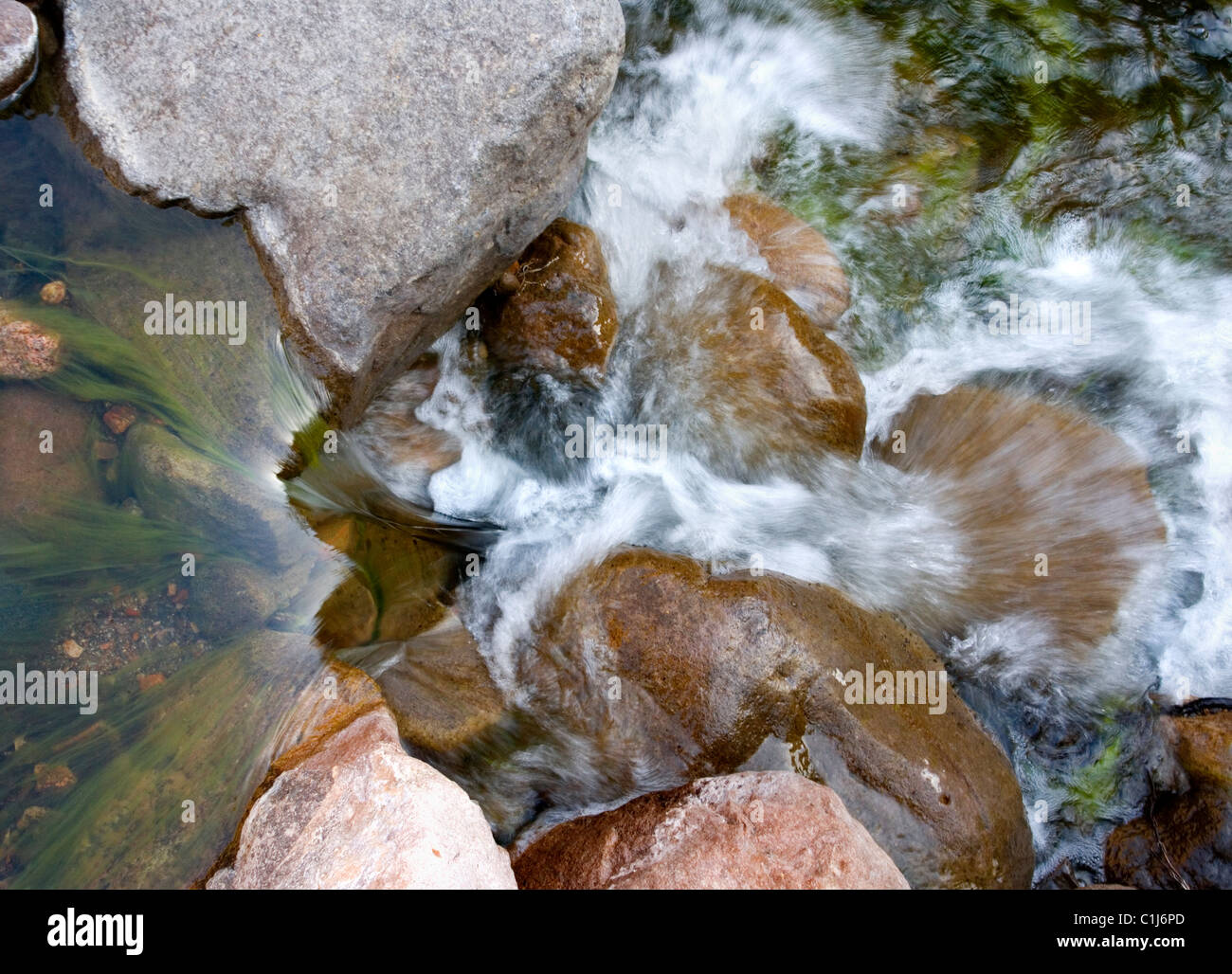 Ein kleiner Bach fließt über die bunten Felsen schauen gerade nach unten. Stockfoto