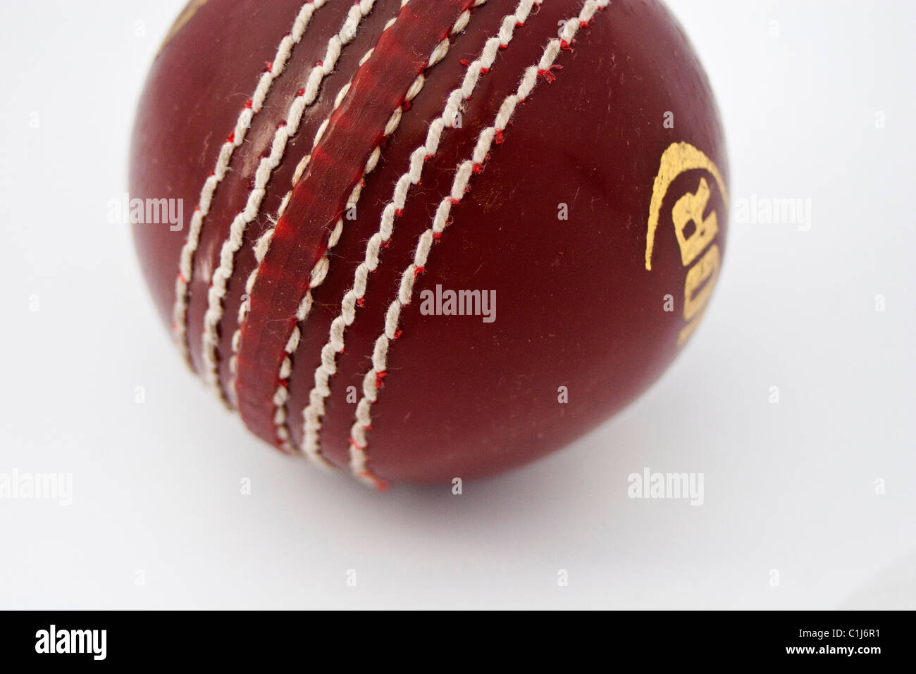 ein zugeschnittenen Schuss von einem dunklen roten Cricketball sauberen, weißen Hintergrund Stockfoto