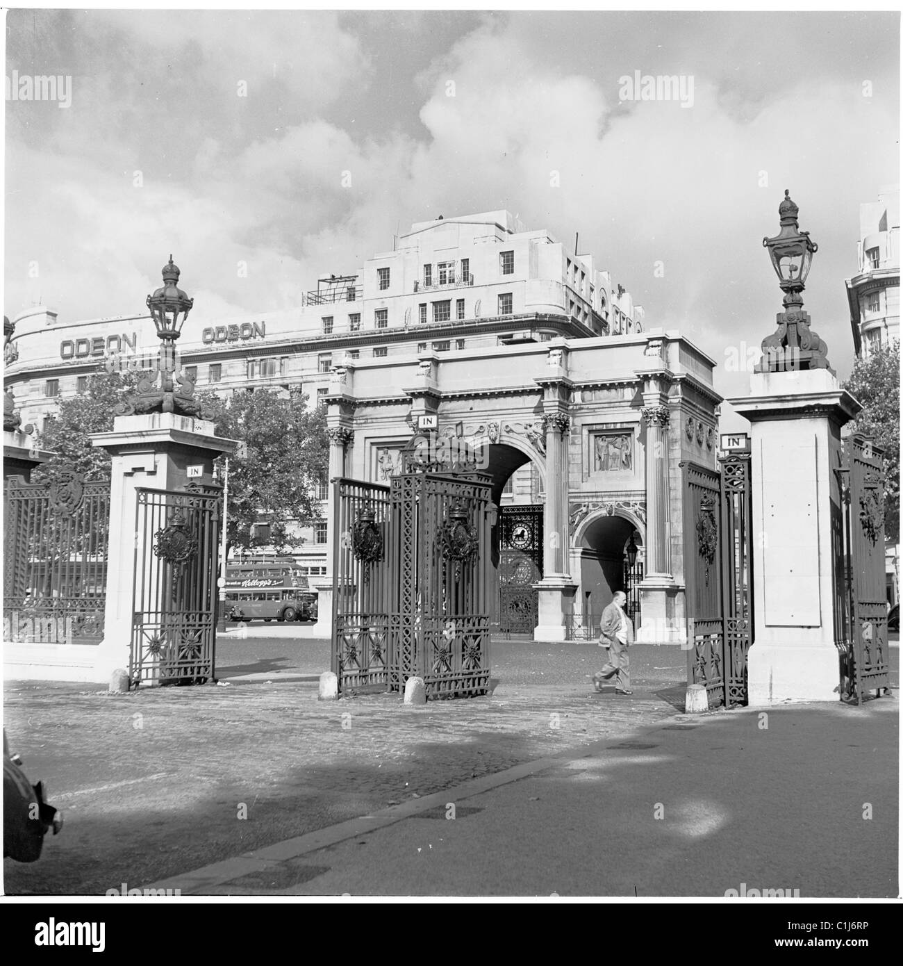 In den 1950er Jahren spaziert man an den Toren am nördlichen Ende des Hyde Park vorbei, am Marble Arch, dem berühmten Denkmal. Das Odeon-Kino ist im Hintergrund zu sehen. Stockfoto