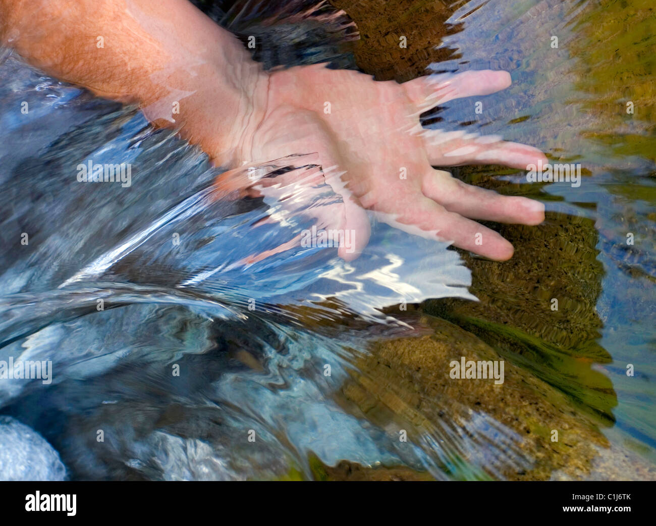 Die Hand eines Mannes in fließendem Strom Wasser zeigt die Strömung und Klarheit Stockfoto
