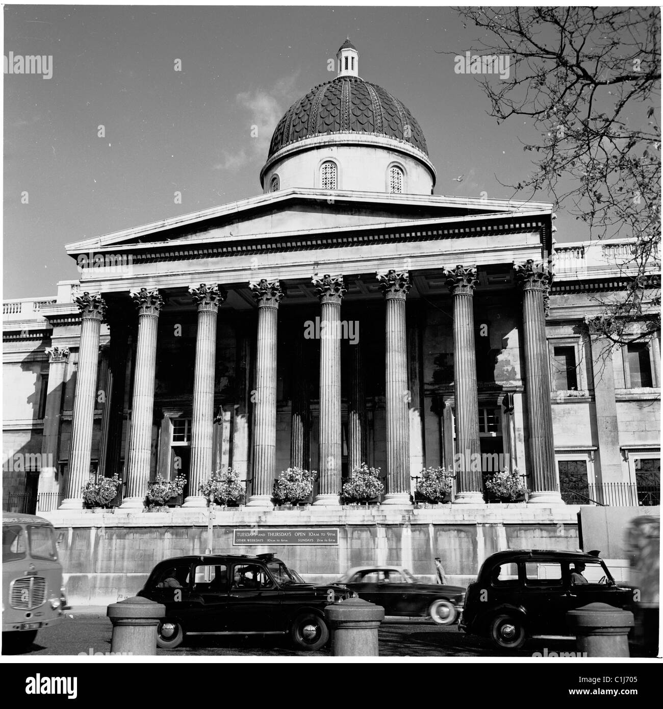 1950er Jahre Autos und Taxis fahren am großen, reich verzierten Säuleneingang zum Kunstmuseum, der National Gallery am Trafalgar Square, Westminster, England, Großbritannien, vorbei. Stockfoto