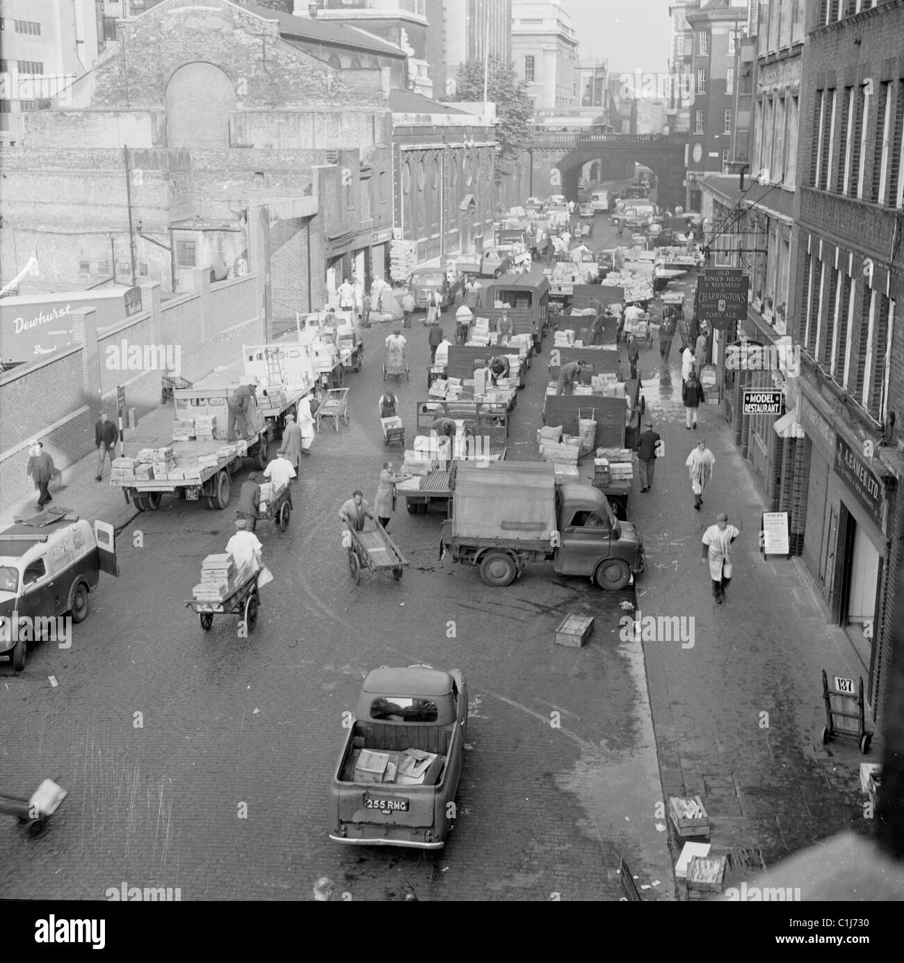1950er Jahre, Blick von oben auf Aktivitäten, während Arbeiter, Träger und Lastwagen die Lower Thames Street am Billingsgate Fish Market in London, England füllen. Stockfoto