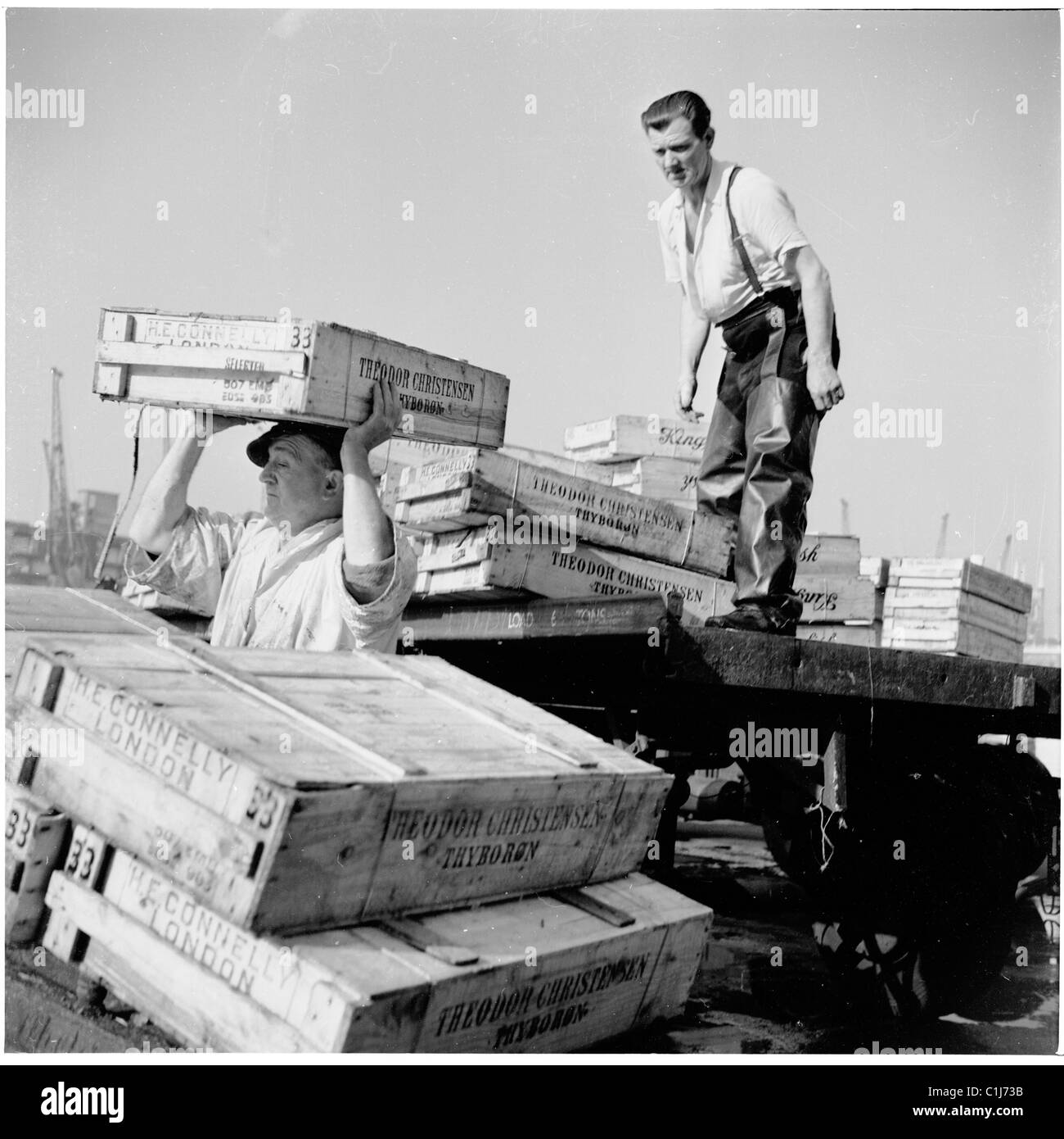 In den 1950er Jahren entladen zwei männliche Arbeiter Fischkisten von der Rückseite eines Lastwagens an der New London Bridge am Billingsgate Fish Market in der Lower Thames Street, London. Stockfoto