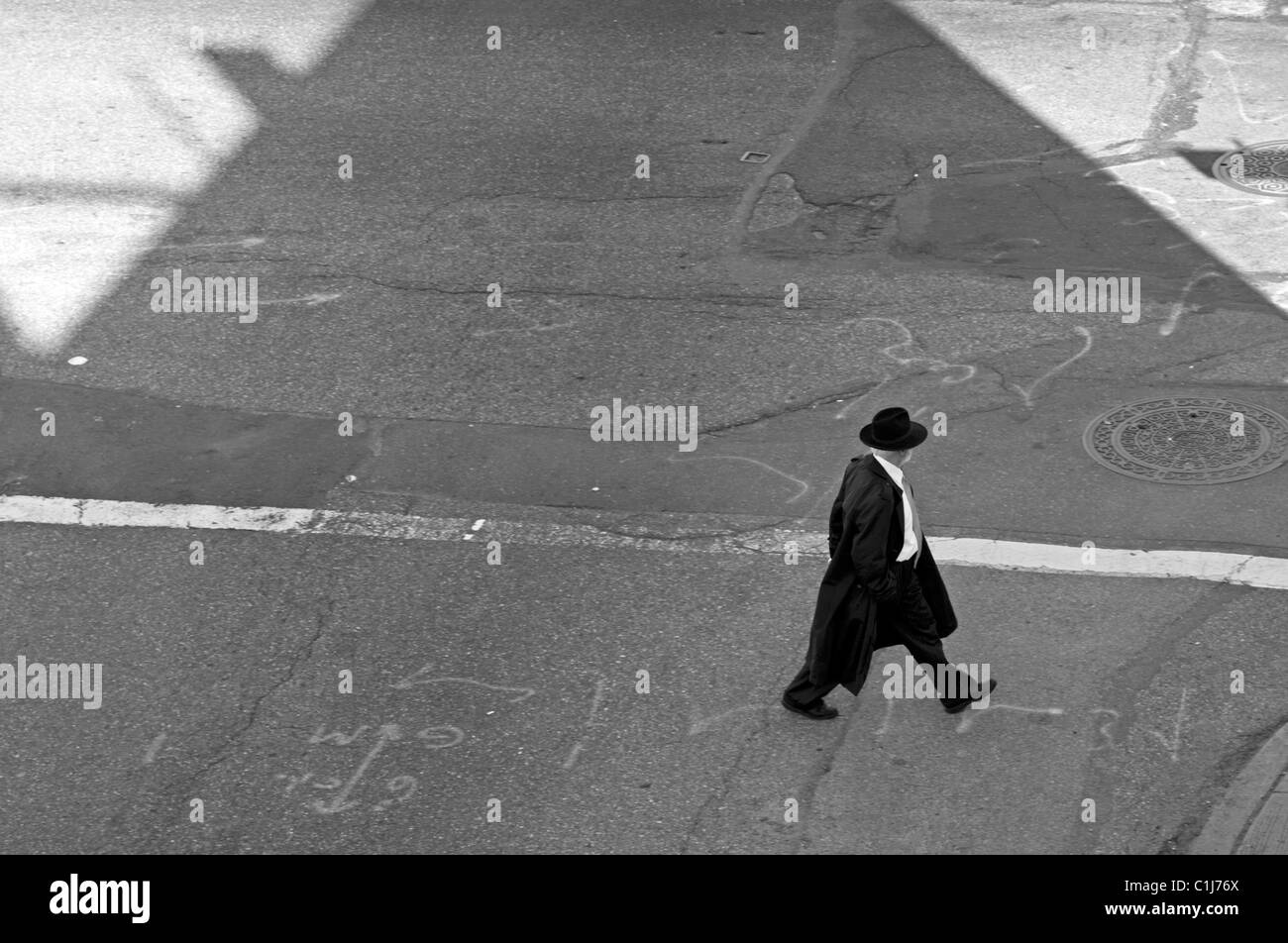 Ein Mann geht allein in New York City im Schatten eines Gebäudes. Stockfoto
