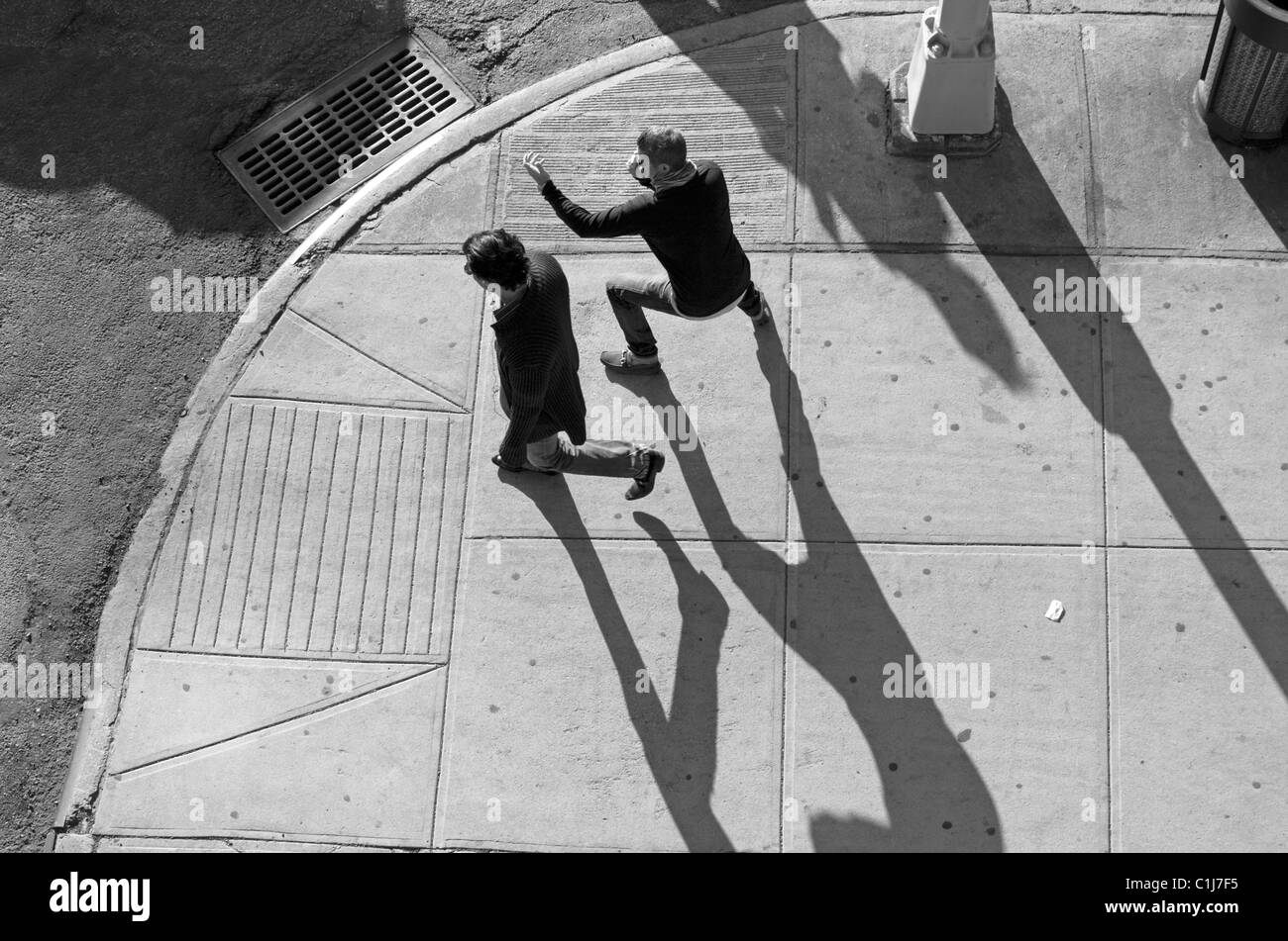 2 Männer werfen lange Schatten, als sie am späten Nachmittag in New York City gehen. Stockfoto