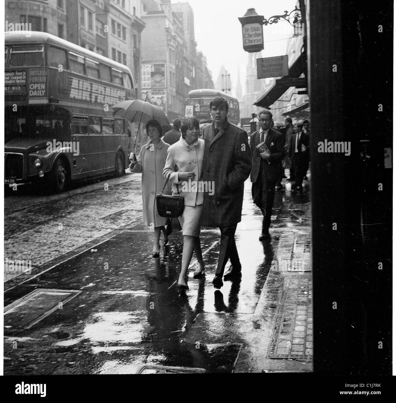 1960 s, Modische junge erwachsene Paare nach einem anstrengenden aber nass Stadt London Street mit ihren Armen zusammen, Fleet Street, London, England, UK. Stockfoto