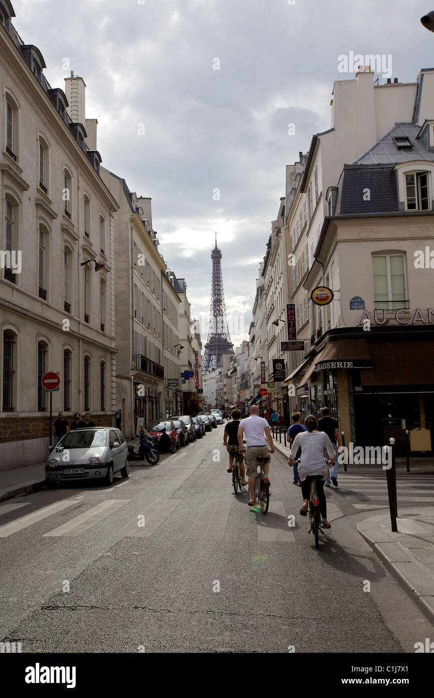 Radfahrer fahren durch eine Pariser Straße mit Blick auf den Eiffelturm unter sanftem Nachmittagslicht Stockfoto