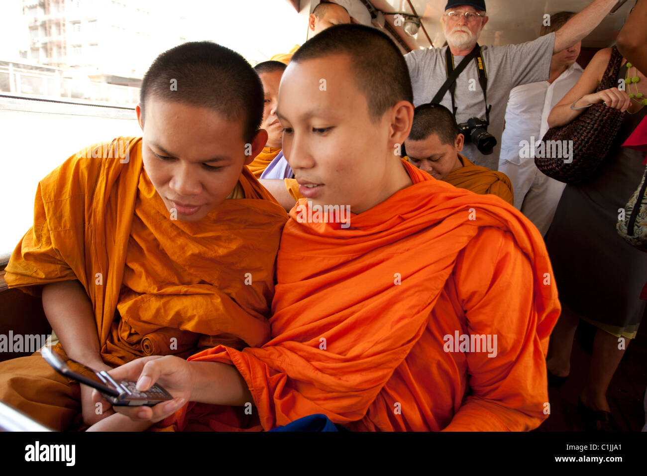 Angelockt von Hightech, spielen zwei buddhistische Mönche mit einem Mobiltelefon an Bord der Fähre Chao Praya Fluss. Stockfoto