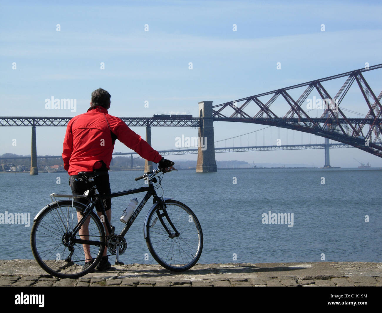 Radfahrer, die gerade eines Zuges überquert die Forth Brücke vom Südufer Stockfoto
