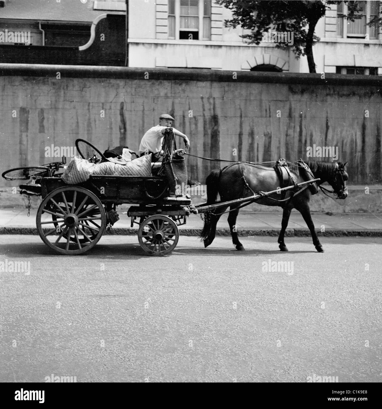 1950er Jahre, ein Mann mit Fetzen und Knochen auf seinem Pferd und Wagen, war er ein Straßenhändler, der unerwünschte Haushaltsgegenstände oder Altmetall wie alte Fahrräder sammelte. Stockfoto