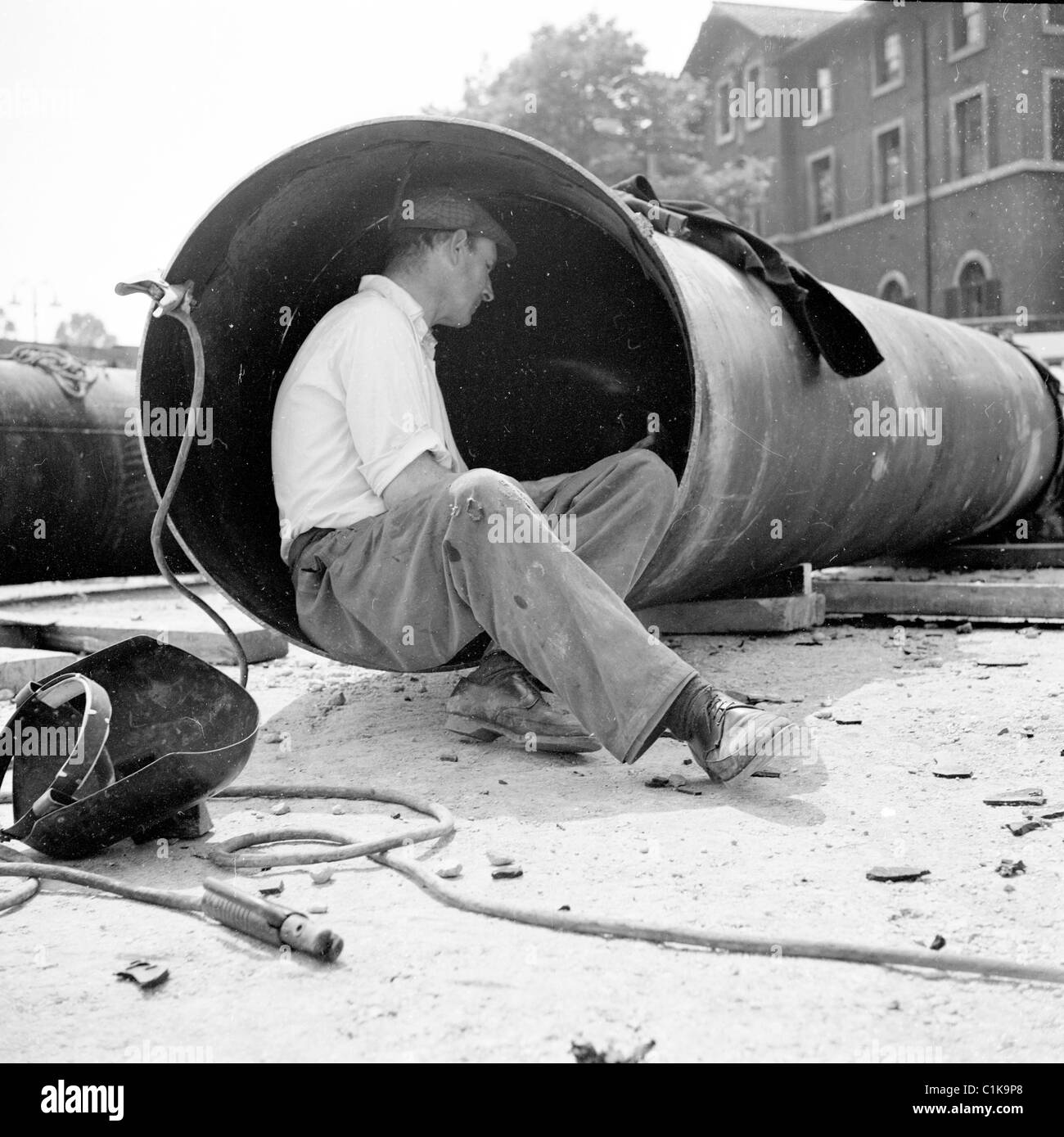 1950er Jahre London. In dieses Geschichtsbild durch J Allan Cash sitzt ein männliche Arbeiter in einem großen runden Rohr auf einer Baustelle. Stockfoto