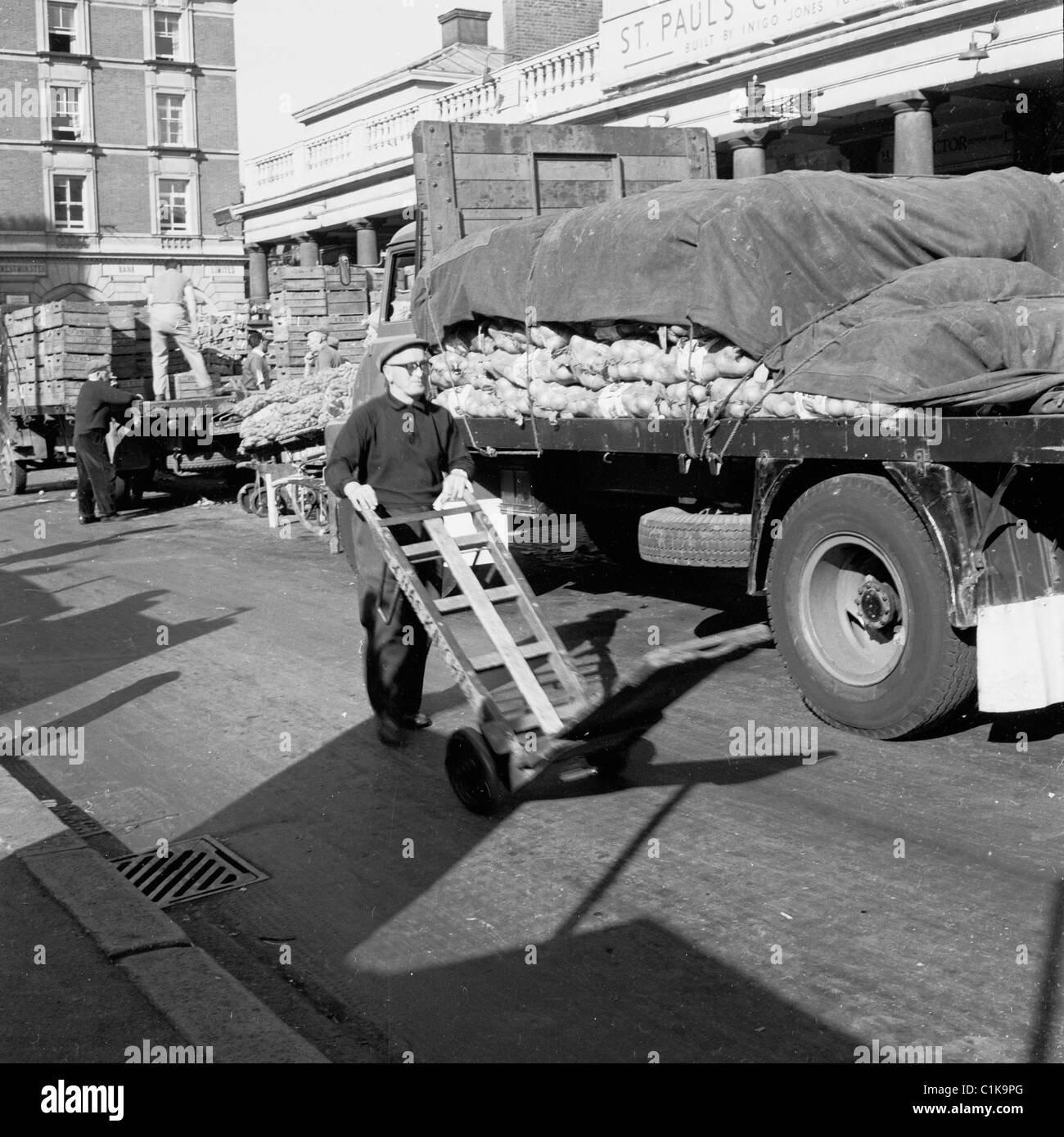 der 1950er Jahre. Geschichtsbild des Arbeiters treibt einen leeren Wagen außerhalb St. Pauls-Kirche in Londons berühmten Covent Garden Market. Stockfoto
