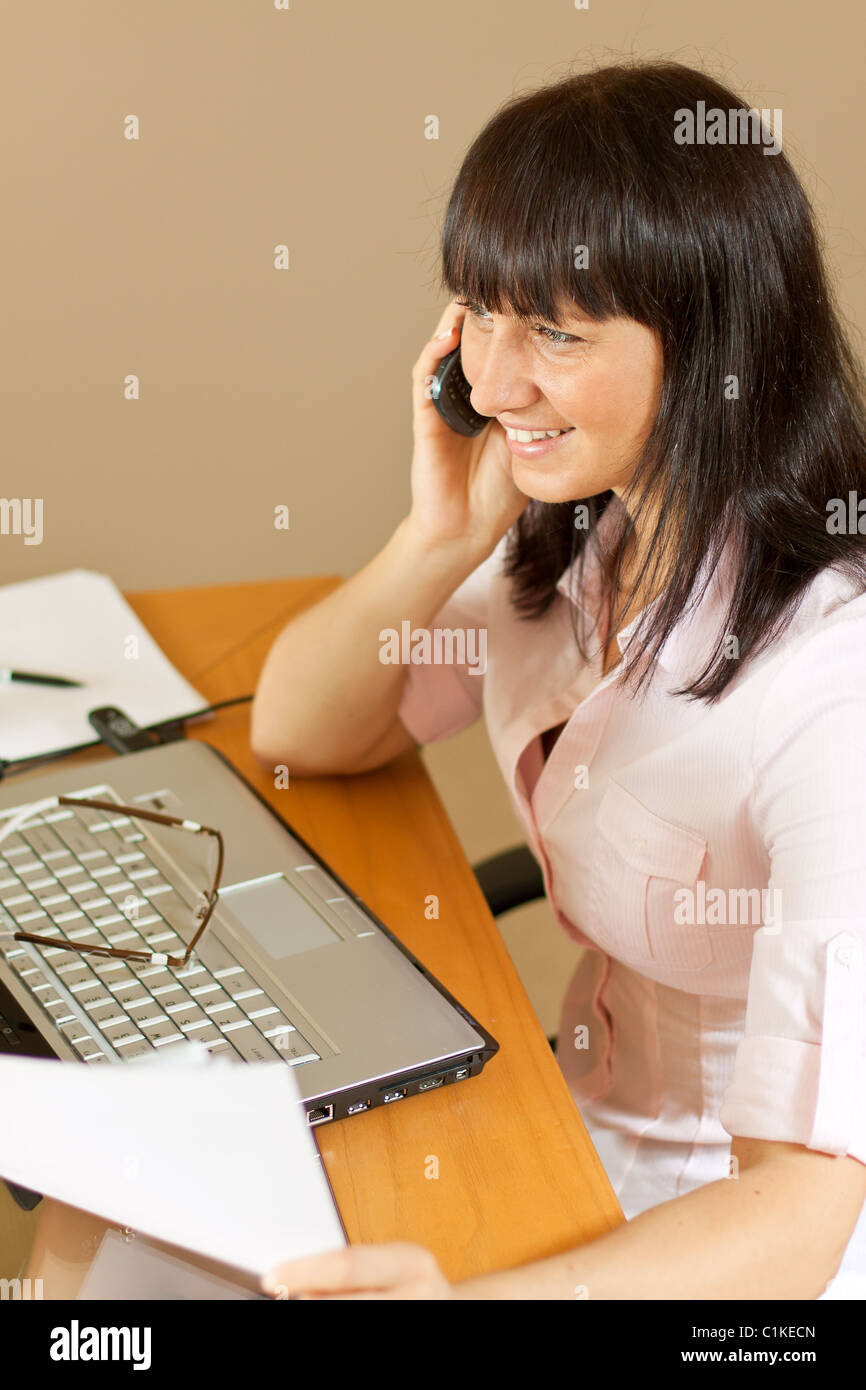 Junge hübsche Frau spricht über das Handy im Büro Stockfoto