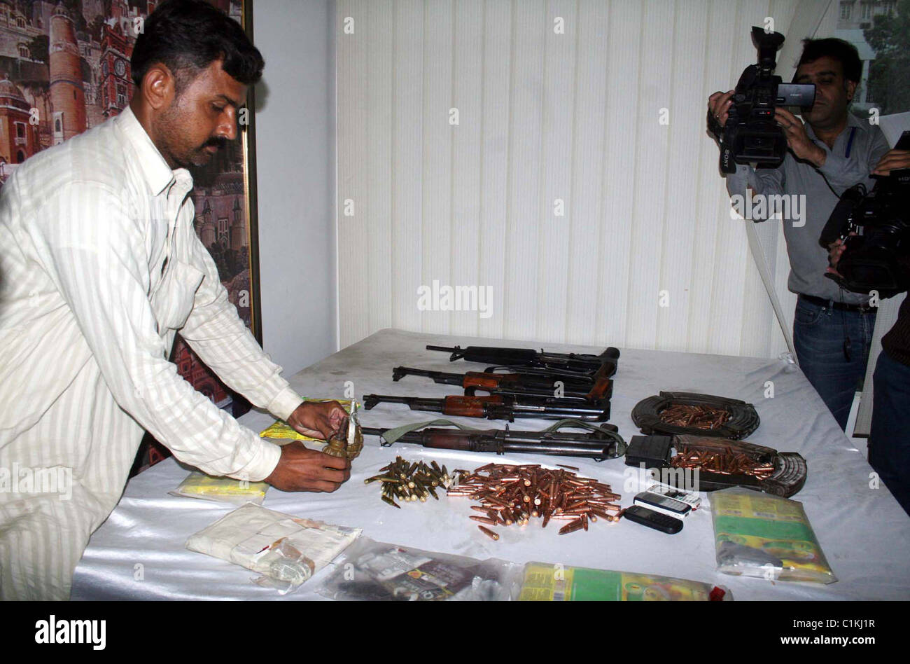Plain-Tuch Polizist zeigt beschlagnahmten Handgranaten, Waffen, Kugeln, Drogen (Haschisch) Pakete und Handys die Recover waren Stockfoto