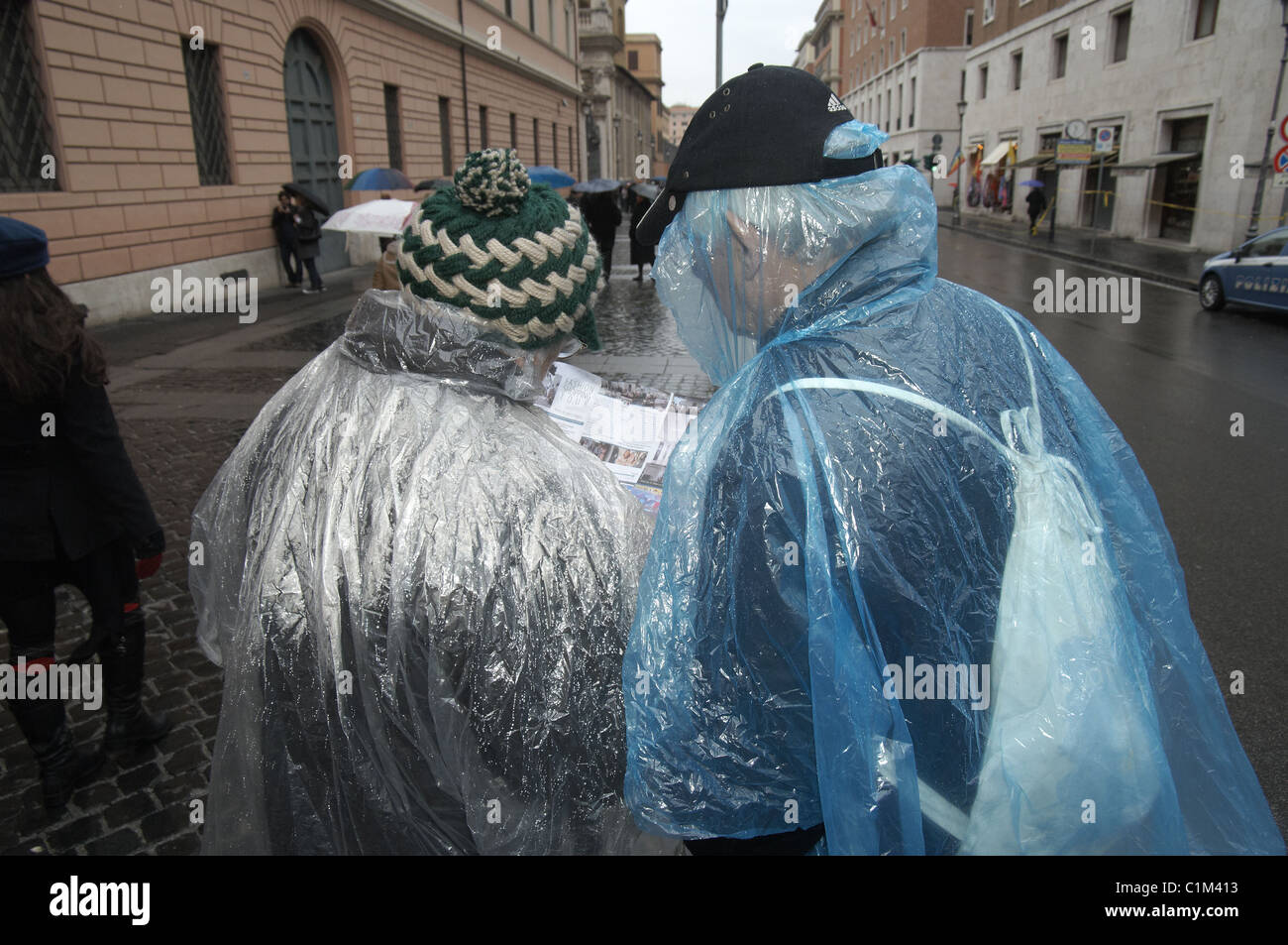 Zwei ältere verlorene nassen Touristen in Kunststoff Regenponchos nass, wie sie versuchen, eine Karte in Rom, Italien, Europa lesen Stockfoto