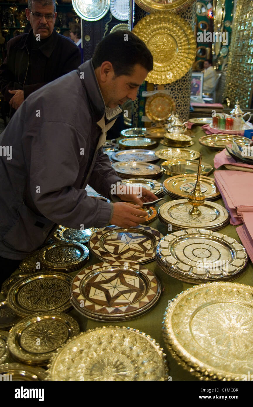 Ein Ladenbesitzer und Kunden im Ladengeschäft Messinggeschirr in Fes, Marokko Stockfoto