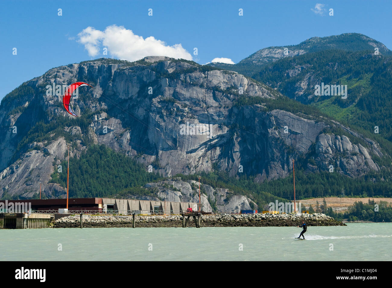Ein Kiteboarder genießt seinen Sport am "Spieß" in Squamish, BC.  Hinter ihm ist "der Chef", einem bekannten Klettern Reiseziel. Stockfoto