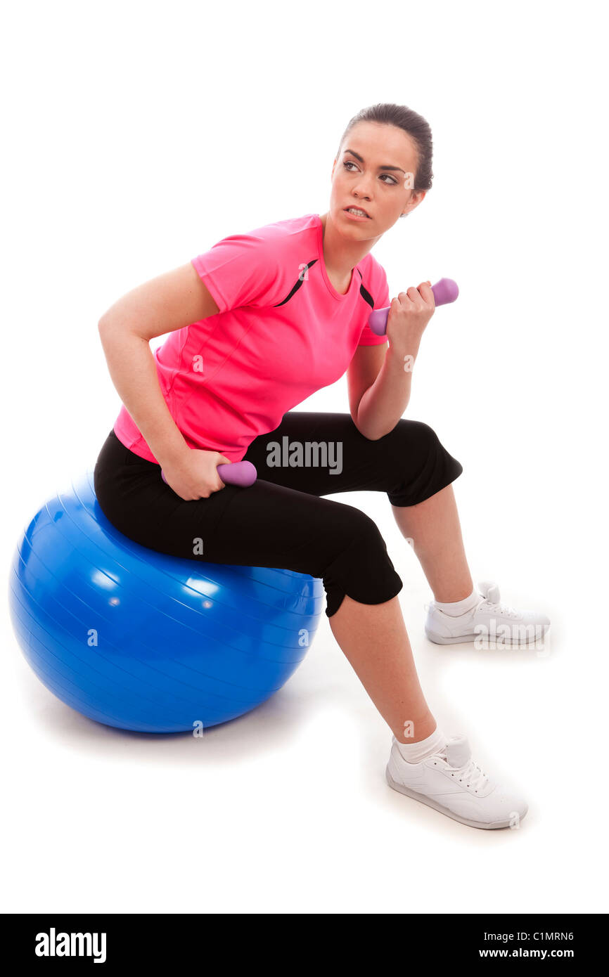 Eine junge Frau, die Übung Gewichte heben setzte einen blauen Gymnastikball Stockfoto