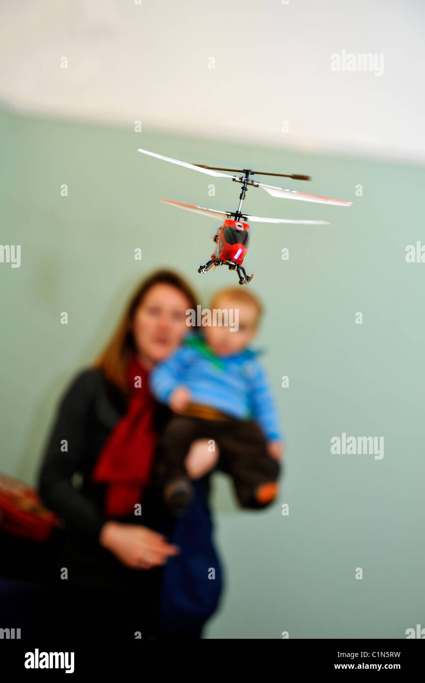 Ferngesteuerte Spielzeug Helikopter fliegen in Innenräumen, Mutter und Kind beobachten Stockfoto