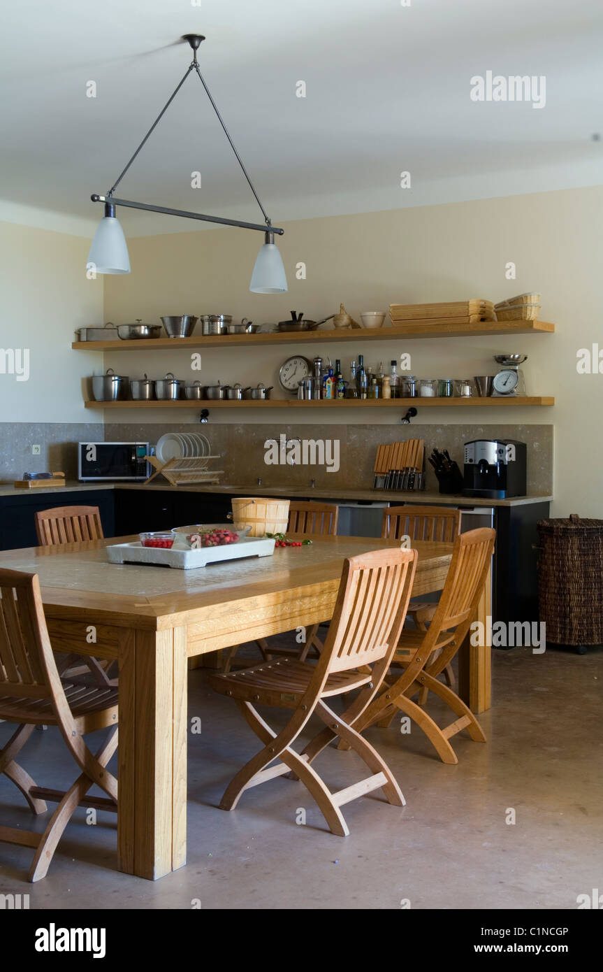 Provenzalisches Landhaus-Küche mit Esstisch aus Holz, Klappstühle und offenen Regalen Stockfoto
