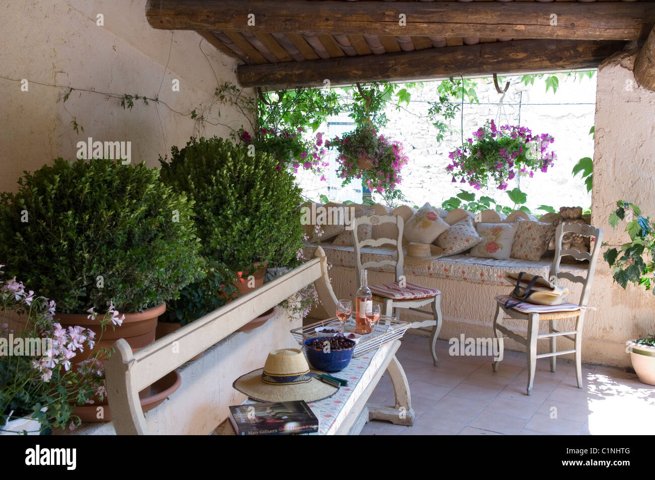 Überdachter Terrassenbereich mit Holzbank und provenzalischen Stühlen Stockfoto