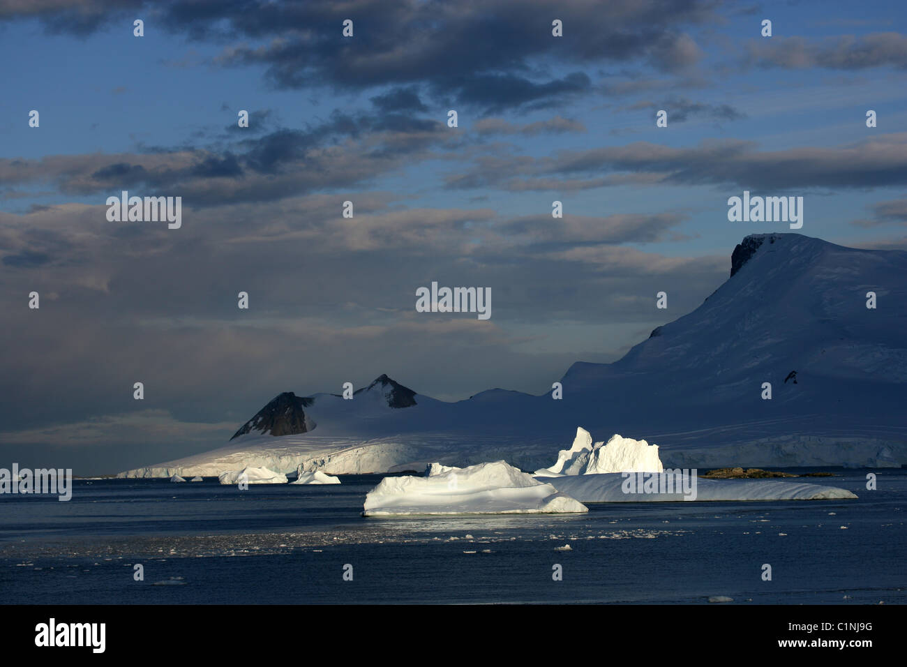 Land und sonnenbeschienenen Eisberge in [Marguerite Bay], [West Graham Land], Antarktis mit abgewinkelten Sonne und blauer Himmel Stockfoto