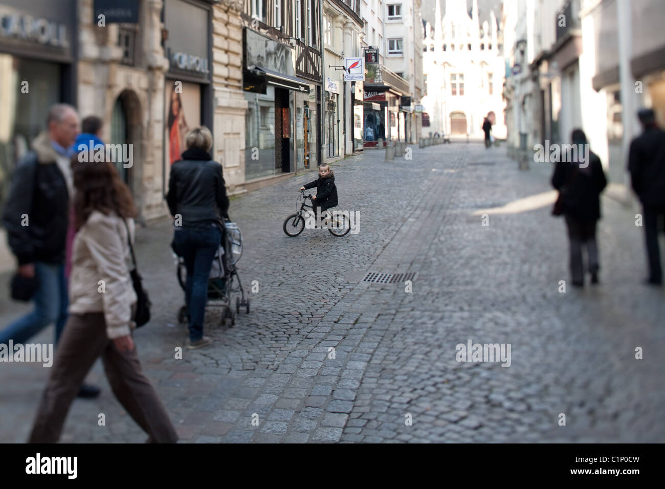 Kleiner Junge sein Fahrrad über ein Kopfsteinpflaster Straße in Rouen, Frankreich Stockfoto