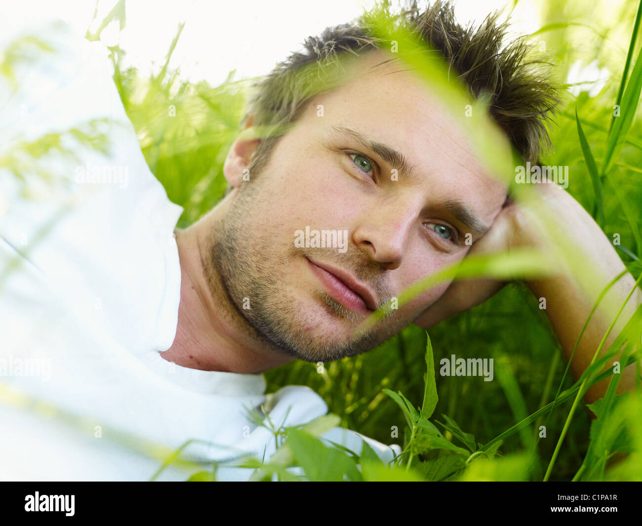 Junger Mann auf dem Rasen liegen und wegsehen Stockfoto