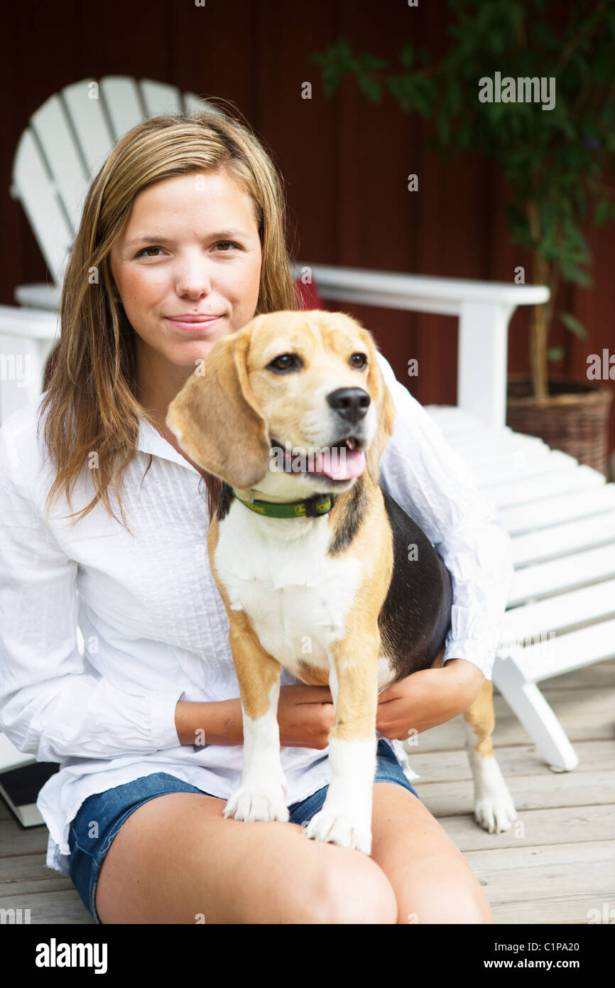 Porträt der jungen Frau mit Hund auf Veranda Stockfoto