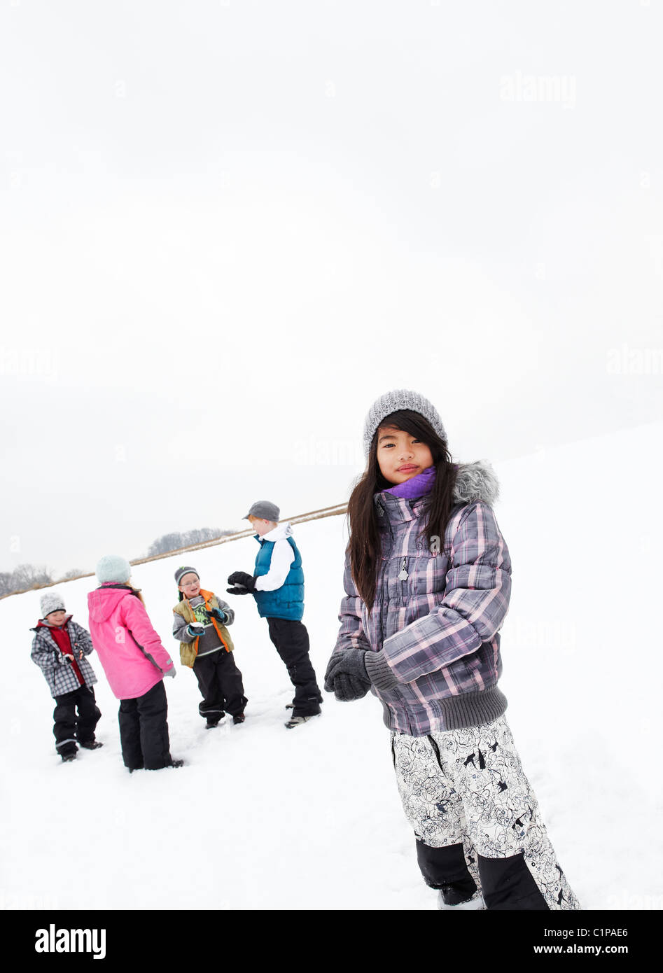 Porträt eines Mädchens mit Freunden spielen im Schnee Stockfoto