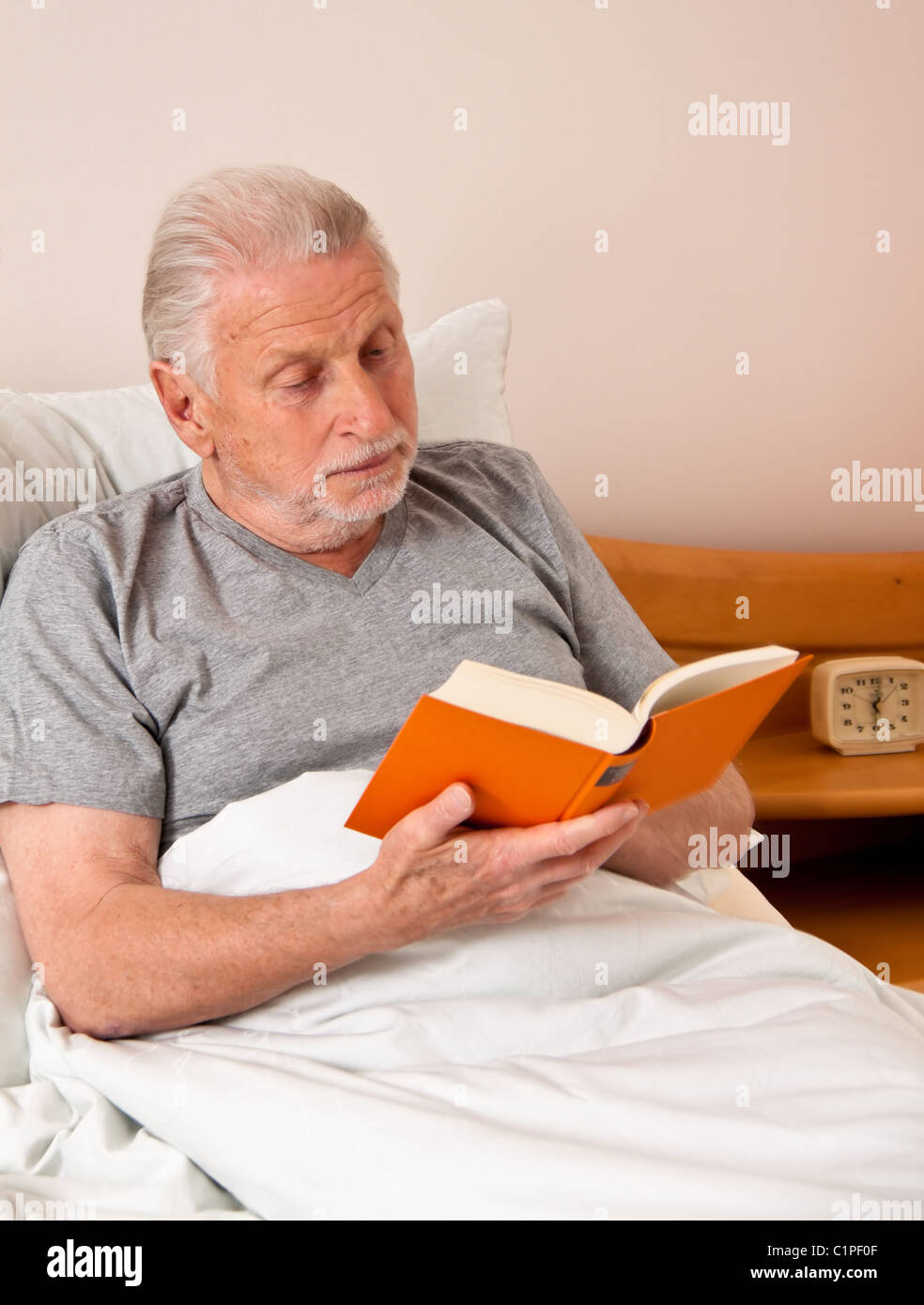 Senior lesen ein Buch im Bett Stockfoto