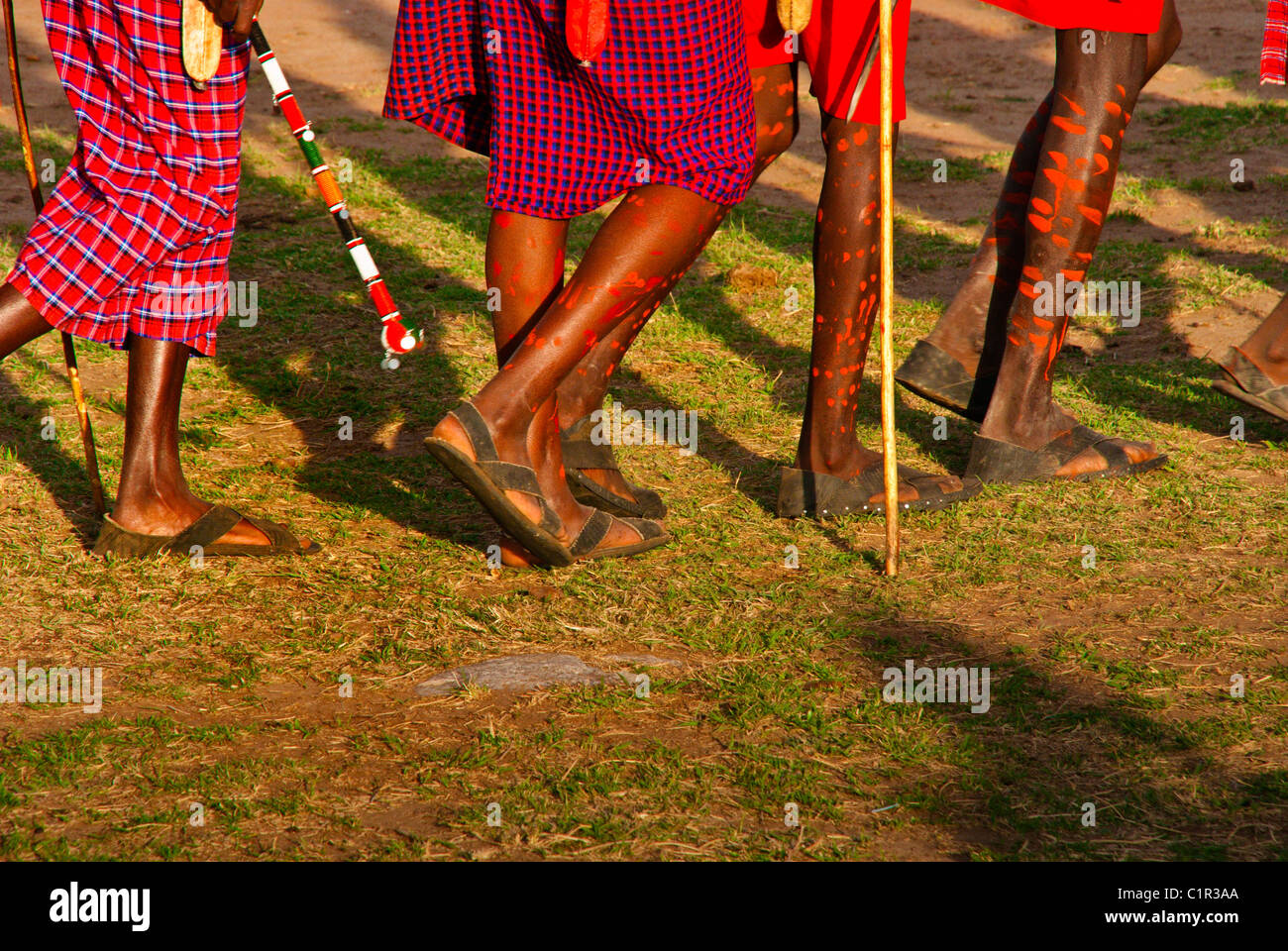 Masai Männer mit verzierten Beinen dabei einen willkommenen Tanz in einem Dorf außerhalb der Masai Mara National Reserve, Kenia, Afrika Stockfoto