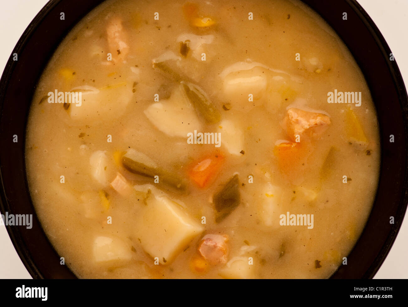 Legen Sie die Suppe mit klobigen Gemüsesuppen flach in eine schwarze Keramikschüssel. Stockfoto