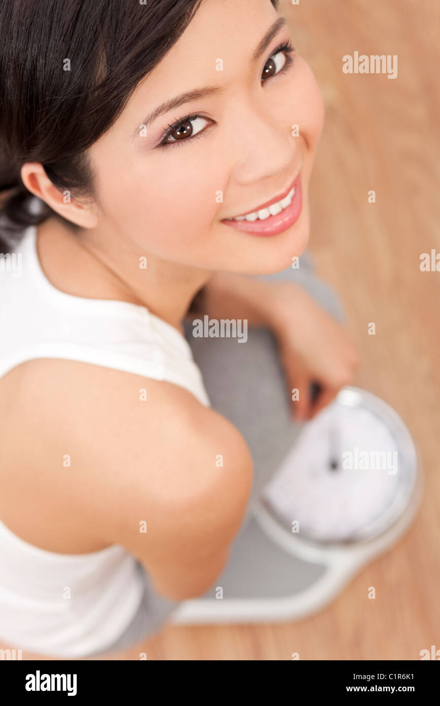 Über den Kopf Blick auf glücklich & schöne orientalische asiatische chinesische Frau wiegen sich auf Skalen im Fitness-Studio oder Gesundheit club Stockfoto