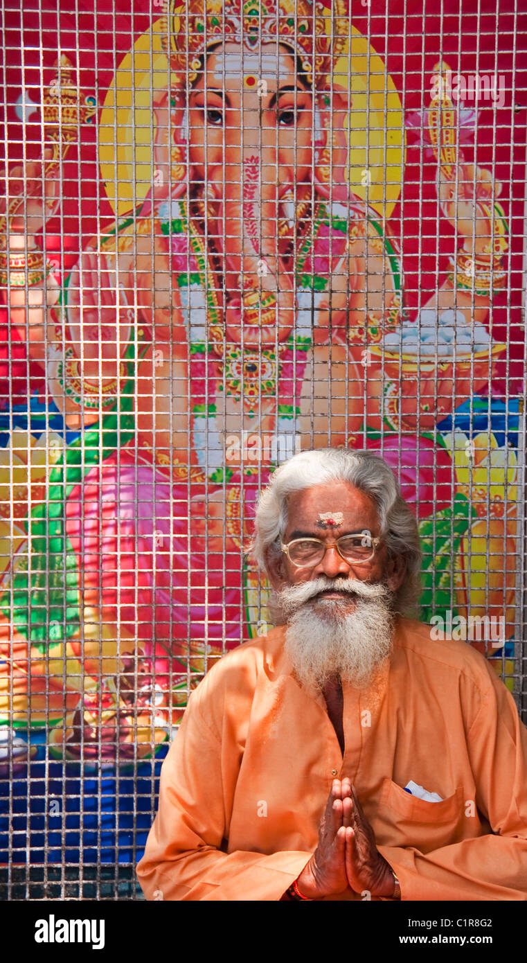 Sadhu oder heiliger Mann vor Plakat des Hindu-Gottes Ganesh in Keralas Hauptstadt Trivandrum. Stockfoto