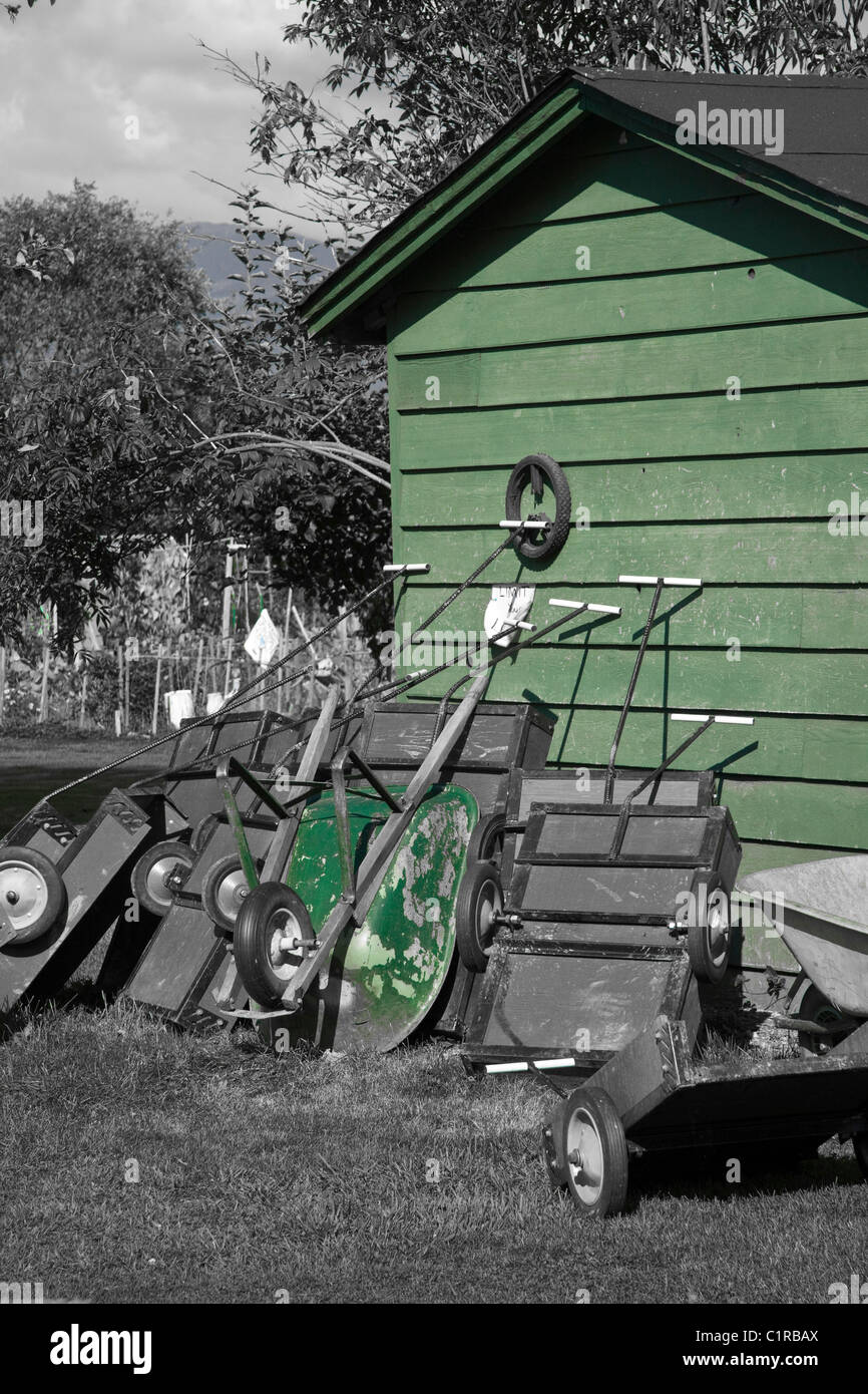 Grün im Garten-Konzept. Verschiedene Whellbarrows und Karren lehnte sich gegen einen Schuppen auf einem gemeinschaftlichen Garten Stockfoto