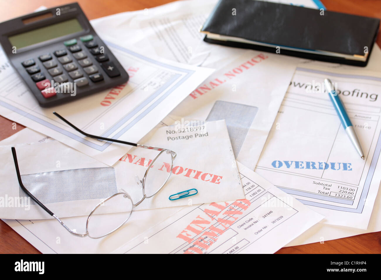 "Überfällige unbezahlte Rechnungen auf Tisch mit Taschenrechner und Scheckbuch" Stockfoto
