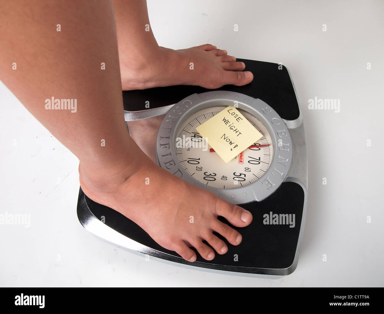 Eine Frau auf eine Waage im weißen Hintergrund mit einem verlieren Gewicht jetzt Hinweis auf dem display Stockfoto