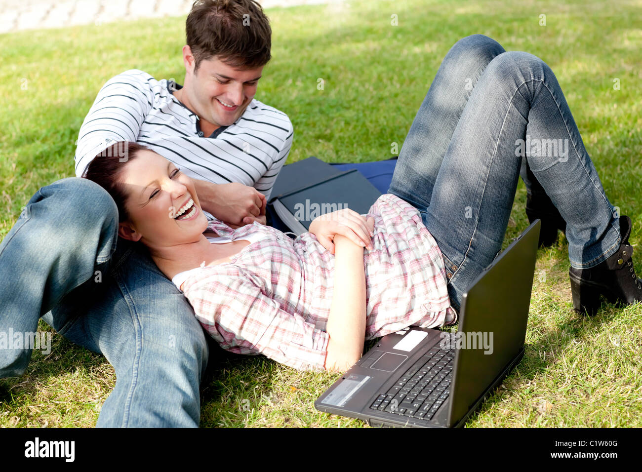 Paar hellen Studenten mit einem Laptop auf dem Rasen liegend Stockfoto