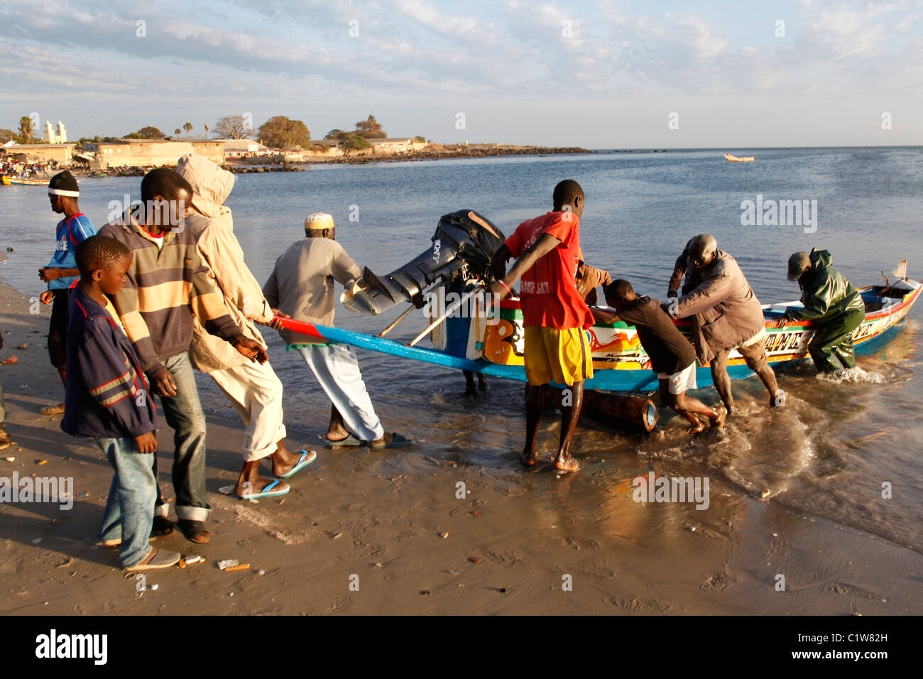 Männer ziehen eine senegalesische Einbaum bis zum Ufer. Dakar, Senegal, Afrika Stockfoto