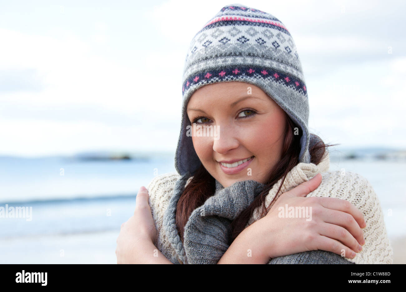 Kalte Frau mit Kopftuch und bunten Hut stehen am Strand Stockfoto