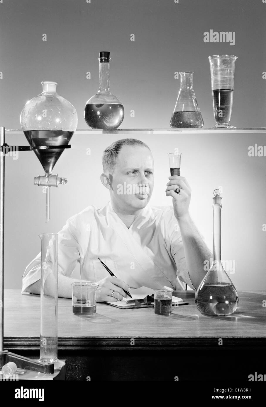 Männliche Wissenschaftler untersuchen Reagenzgläser mit Flüssigkeit Stockfoto
