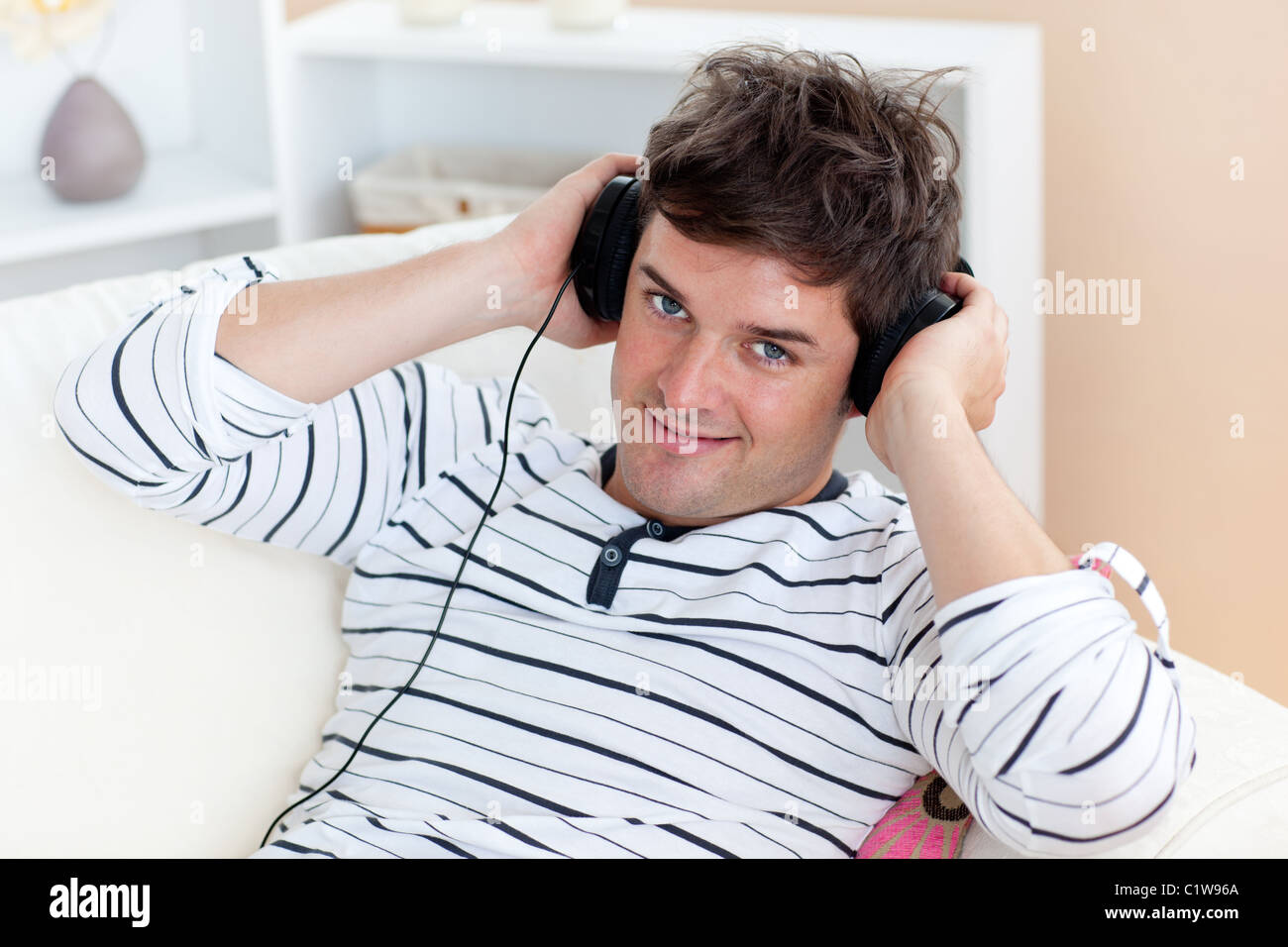 Lustiger Mann Musik hören mit Kopfhörern auf sitzt in seinem Wohnzimmer Stockfoto
