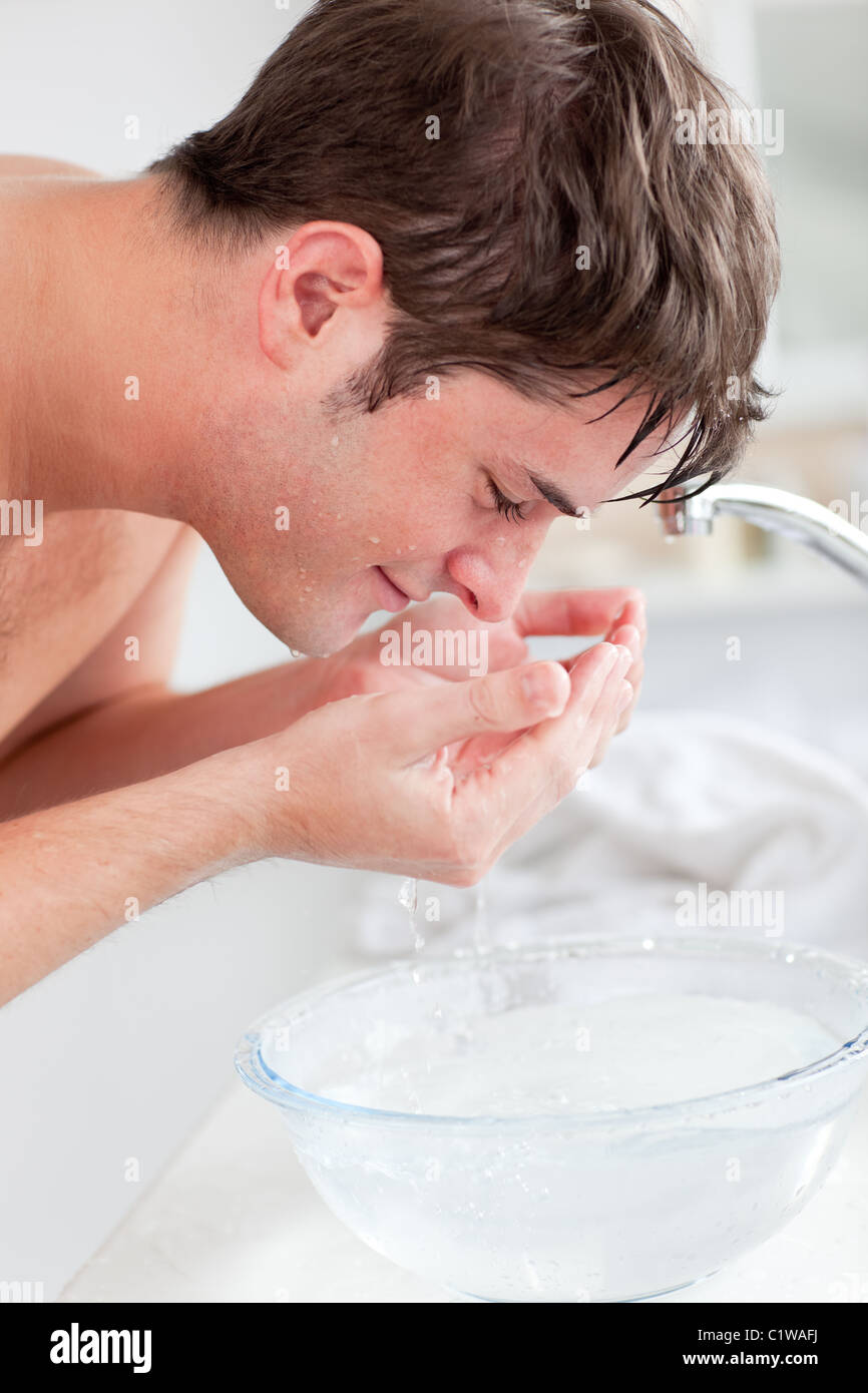 Positive Menschen Aufsprühen von Wasser auf seinem Gesicht nach dem Rasieren im Bad Stockfoto