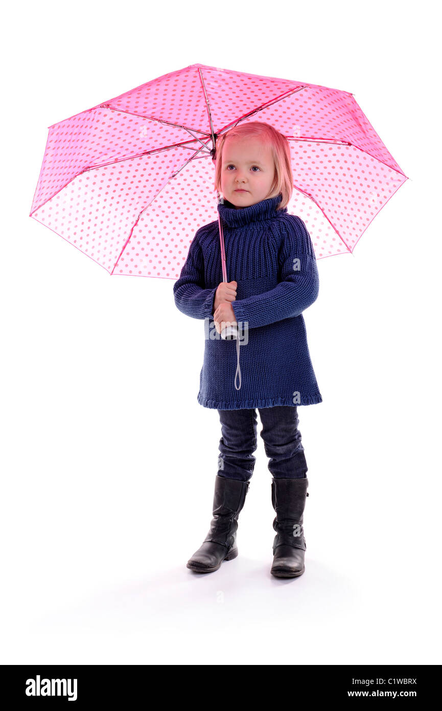 kleine Mädchen stehen unter einem rosa mit Punkte Regenschirm. isoliert auf weiss Stockfoto